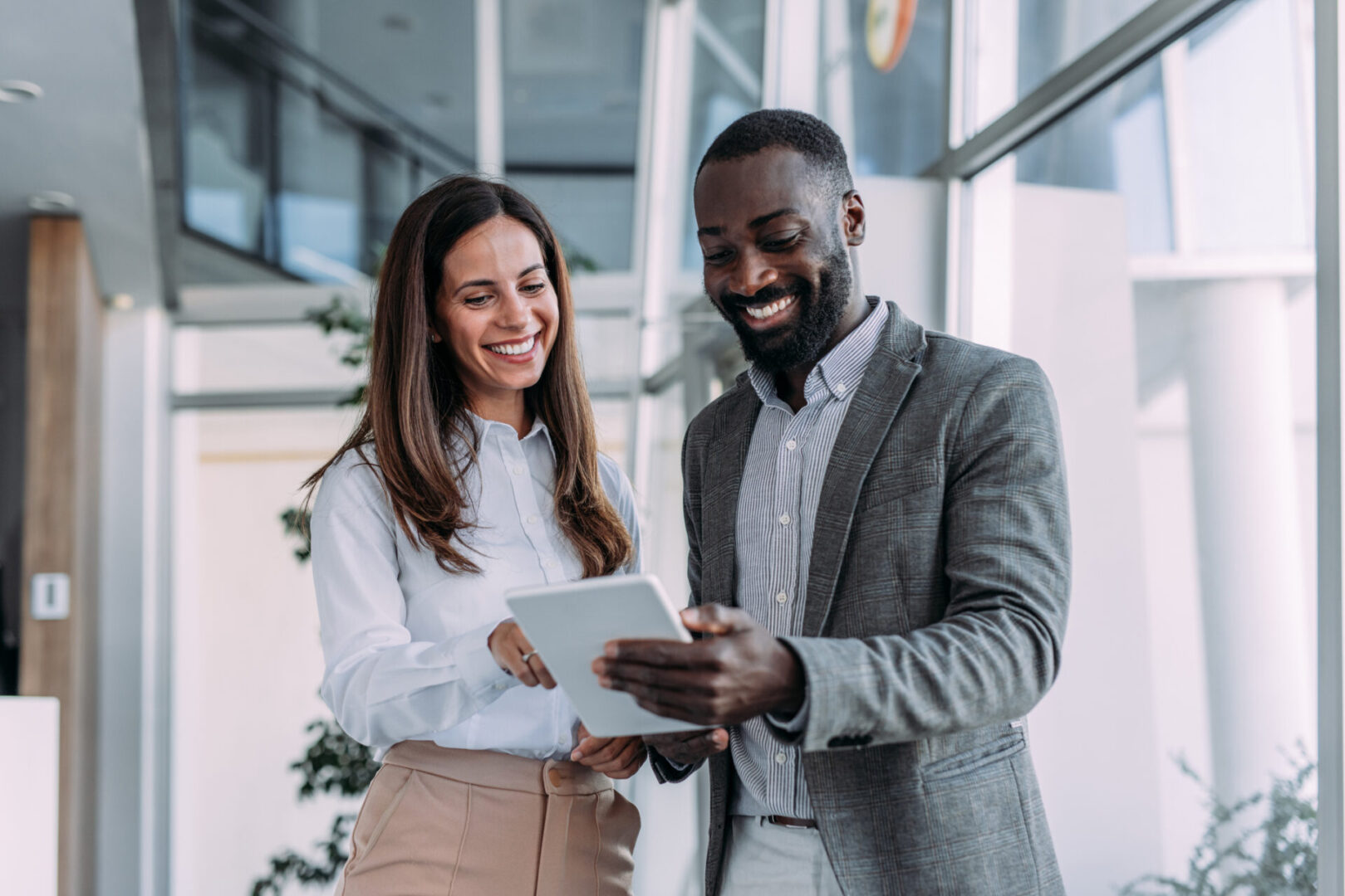 Two colleagues smiling while using a tablet.