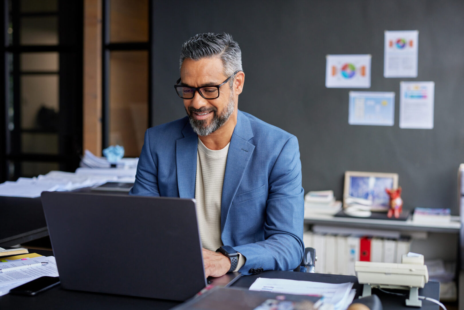 Man smiling while working on a laptop.